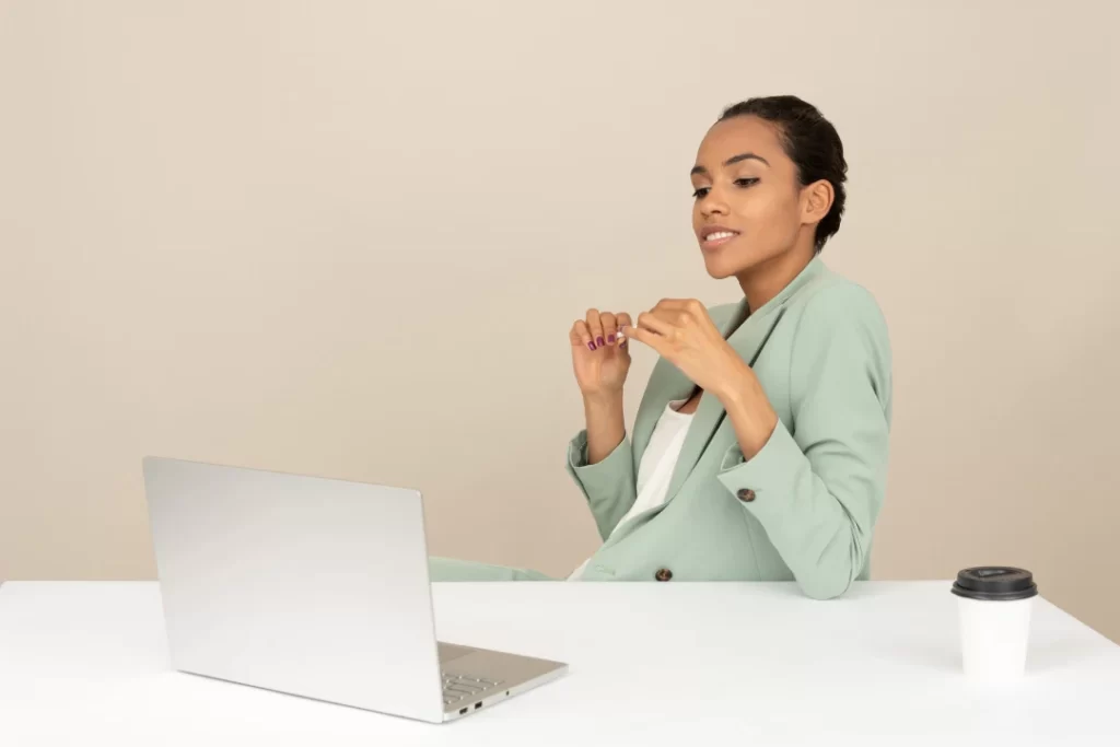 The young attractive lady sitting in front of a laptop with her coffee on the desk.