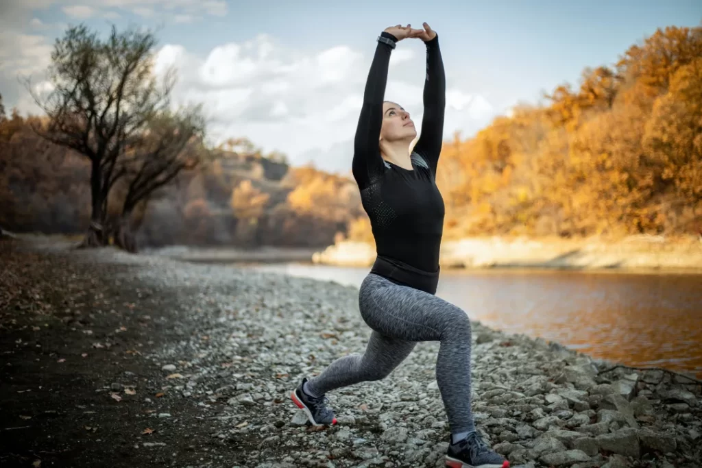 the healthy woman actively doing exercise on the river bank.