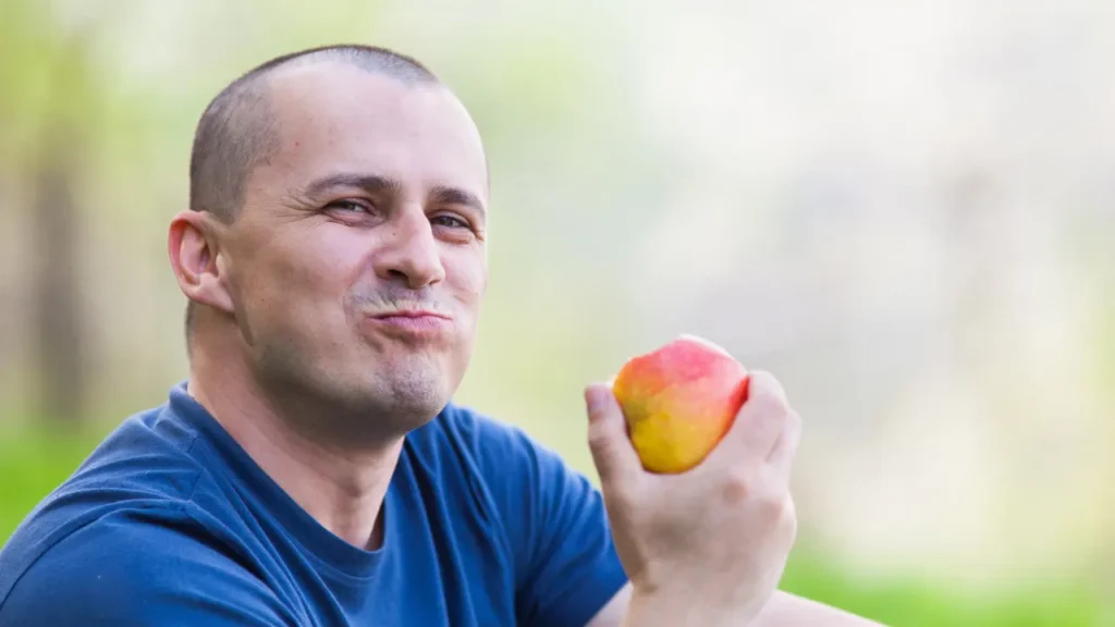 Man is eating an apple.